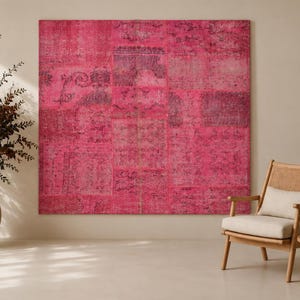 May include: A large, square, hot pink patchwork rug featuring a faded, intricate, dark-toned pattern across its surface. The rug is composed of multiple rectangular sections stitched together, displaying varying shades of magenta and fuchsia.