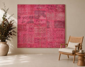 May include: A large, square, hot pink patchwork rug featuring a faded, intricate, dark-toned pattern across its surface. The rug is composed of multiple rectangular sections stitched together, displaying varying shades of magenta and fuchsia.