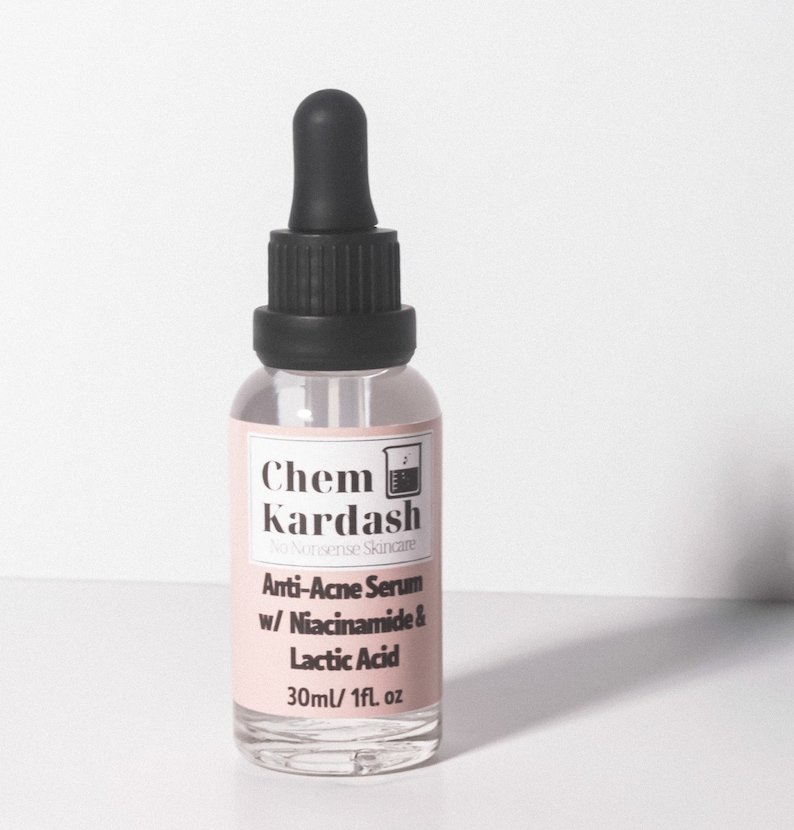 May include: A clear glass bottle with a black dropper top and a white label. The label reads "Chem Kardash No Nonsense Skincare Anti-Acne Serum w/ Niacinamide & Lactic Acid 30ml/1fl. oz"