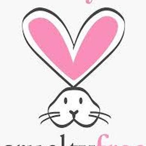 Puede incluir: Gr&aacute;fico de una cara de conejo blanco con bigotes negros y un contorno rosa en forma de coraz&oacute;n encima. Las palabras "buy" y "cruelty free" est&aacute;n en rosa y negro, colocadas encima y debajo del conejo.