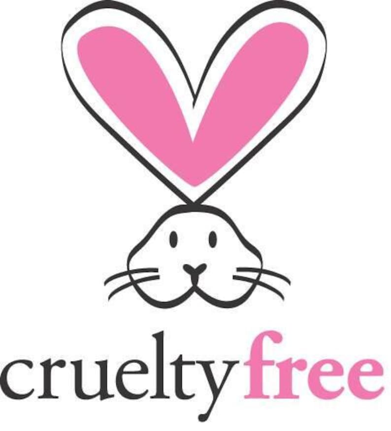 May include: A black and white illustration of a bunny head with pink heart-shaped ears. The words "cruelty free" are written below the bunny in black and pink text.