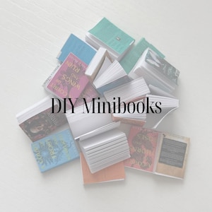 May include: A selection of small books in shades of blue, green, and pink, with text visible on the covers. The words "DIY Minibooks" are displayed in the centre. The books are arranged on a white surface.