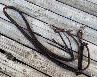 May include: A brown leather braided horse rein with two silver snap hooks and leather tassels.