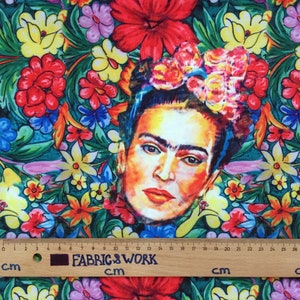 Op de afbeelding: Een kleurrijke stof met een bloemenpatroon en een portret van Frida Kahlo in het midden. De stof is groen, rood, geel, blauw en roze. Het portret is een close-up van Frida Kahlo's gezicht, met haar kenmerkende monobrauw en bloemenkrans.