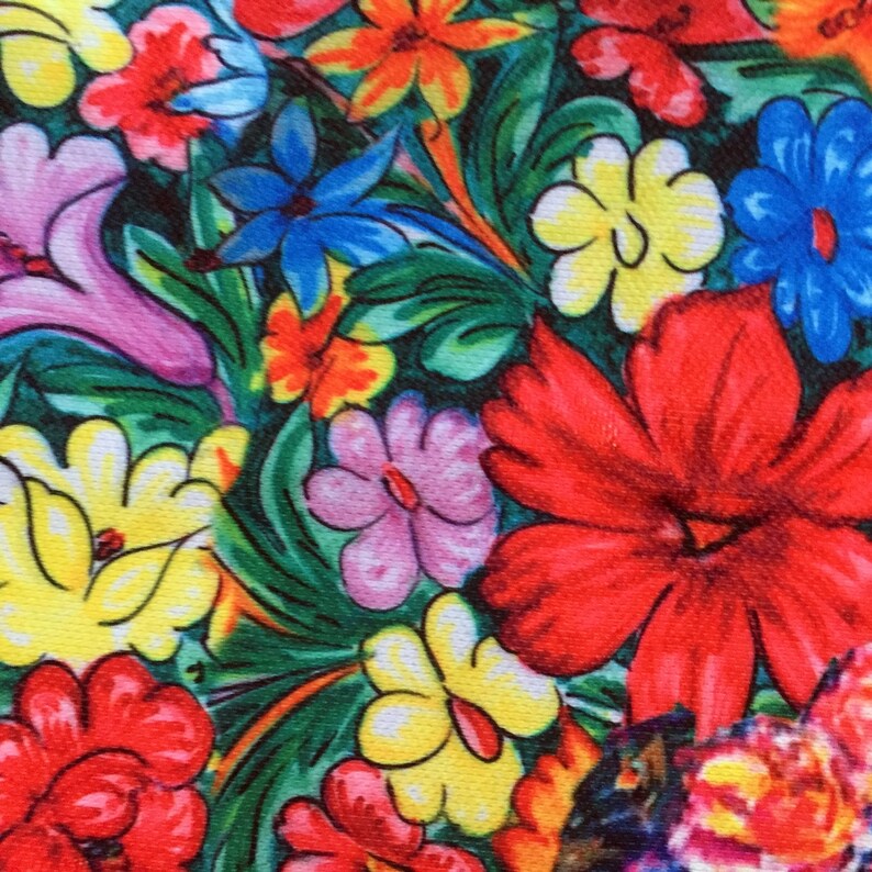 Op de afbeelding: Een kleurrijke bloemenprintstof met verschillende bloemen in tinten rood, geel, roze, blauw en groen. De stof heeft een herhalend patroon van bloemen en bladeren.