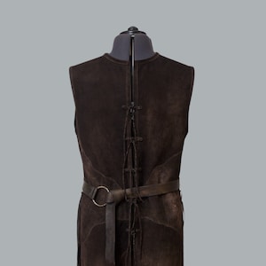 May include: A brown suede vest with a laced-up back and a brown leather belt with a silver buckle.