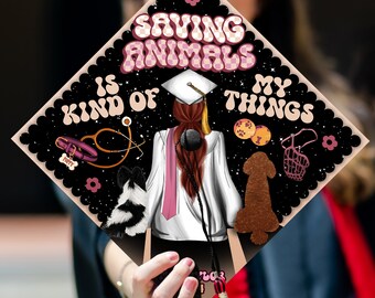 May include: A black graduation cap with a pink and white chequered background. The text "Saving Animals is Kind of My Things" is written in white letters with a pink outline. The cap features a cartoon illustration of a woman with long red hair wearing a white graduation gown and a stethoscope around her neck. There are two dogs, one black and white and one brown, and a pink leash and a pink dog collar.