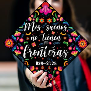 May include: Black graduation cap decorated with colorful floral patterns and the text "Mis sueños no tienen fronteras" in white script. The cap also includes "BSN-2025". The design features pink, orange, yellow, and blue flowers.