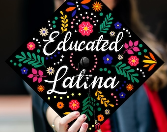 May include: Black graduation cap with colorful floral designs and the text "Educated Latina" in white.