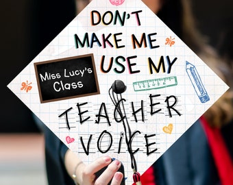 May include: A white graduation cap with a black and white grid pattern. The cap has a black chalkboard with the text "Miss Lucy's Class" and the text "DON'T MAKE ME USE MY TEACHER VOICE" in colorful handwritten letters.