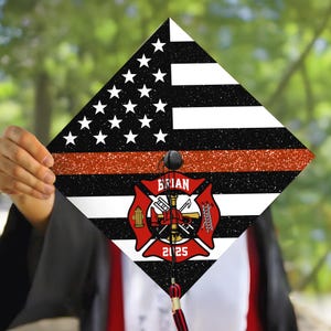 May include: A graduation cap decorated with an American flag, a red line, and a firefighter's emblem. The emblem features a fire hydrant, an axe, a helmet, and a ladder. The text "BRIAN 2025" is printed below the emblem.