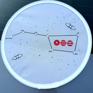 May include: A circular white fan featuring a black constellation graphic with names Jung Kook, Suga, Jin, V, Jimin, J-Hope, and RM. The design includes small clear rhinestones at star points and three red circular icons with horizontal lines.
