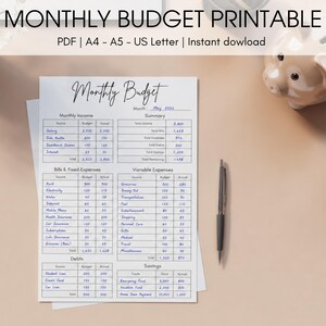 Peut inclure: Un planificateur budgétaire mensuel imprimable avec un titre manuscrit. Le document comprend des sections pour les revenus, les dépenses, les dettes et les économies, avec un stylo posé sur le côté. Le texte comprend "Budget Mensuel" et "Mai 2026."