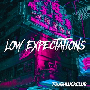 May include: A neon sign with the text "LOW EXPECTATIONS" in white against a pink and blue background. The sign is in front of a building with a distorted, glitchy effect. The text "TOUGHLUCKCLUB" is in the bottom right corner.