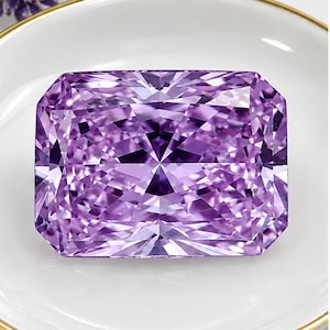 May include: A radiant-cut gemstone with a vibrant purple hue and intricate geometric facets that reflect light. The stone is rectangular in shape with clipped corners, showcasing a deep violet color profile and a highly polished, reflective surface.