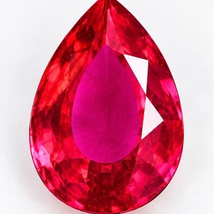 May include: A pear-shaped, faceted gemstone with a vibrant, saturated red colour. The stone features a pointed top and a rounded base, with numerous geometric facets that reflect light across its surface, creating a brilliant, deep crimson appearance.