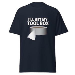 Könnte beinhalten: Marineblaues T-Shirt mit dem Text "I'LL GET MY TOOL BOX" und einer Abbildung einer Rolle silbernen Klebebands mit einem weißen Ende. Das T-Shirt ist kurzärmlig und hat einen Rundhalsausschnitt.