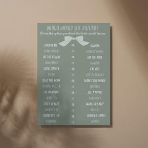 Puede incluir: Un letrero rectangular verde con el texto "WHICH WOULD SHE RATHER?" y una lista de opciones para un juego de despedida de soltera. Las opciones incluyen "Chocolate o Vainilla", "Película de miedo o Comedia", y más.