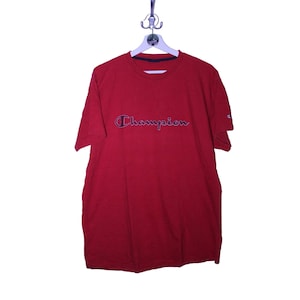May include: A red t-shirt with the word "Champion" embroidered in black and white on the front.