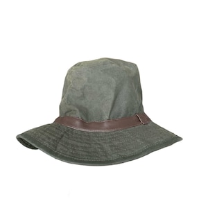 Puede incluir: Un sombrero verde tipo « bucket » con una banda de cuero marrón. El sombrero tiene un ala ancha y una corona redondeada. El sombrero está hecho de un material duradero y resistente al agua.