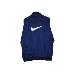 Puede incluir: Una chaqueta azul marino con un logotipo blanco de Nike en forma de swoosh en la espalda.