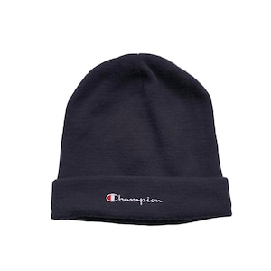Può includere: Un berretto blu navy con un logo Champion bianco ricamato sul davanti.