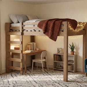 以下が含まれることがあります： 木製のロフトベッド、デスク、梯子。ベッドには茶色のニットブランケットがあります。ベッドの下には小さな机と椅子があります。部屋にはラグ、青いアームチェア、額入りのアートワークがあります。
