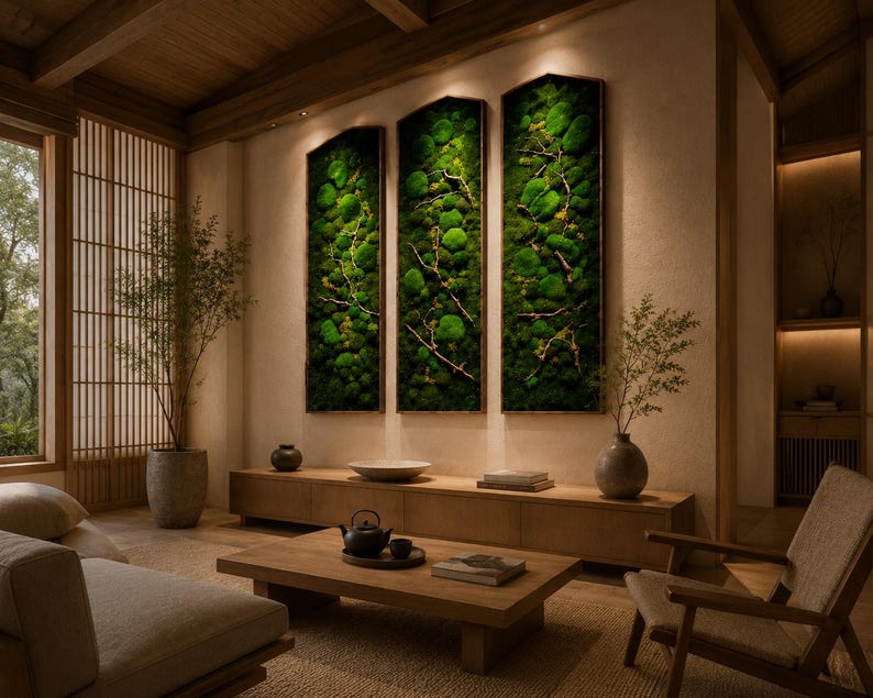 Op de afbeelding: Een moderne woonkamer met een natuurlijke uitstraling. Drie verticaal ingelijste moskunstwerken hangen aan de muur. Een houten salontafel, een bank en een stoel staan in de kamer. Een groot raam met uitzicht op bomen bevindt zich aan de linkerkant.