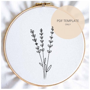 Pode incluir: Um bastidor de bordado com tecido branco com um desenho minimalista a preto de raminhos de lavanda. O bastidor é de madeira e tem um fecho de metal. Um círculo bege com o texto "PDF TEMPLATE ONLY" está no canto superior direito.