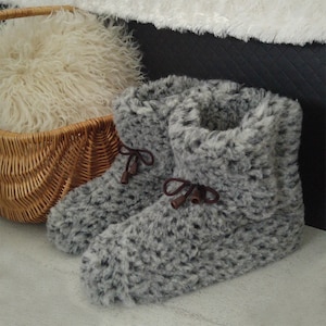 May include: A pair of grey fluffy slippers with brown laces. The slippers have a soft, fluffy texture and are perfect for keeping your feet warm in the winter.