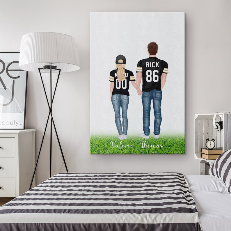May include: A personalised illustration of a couple wearing black and gold football jerseys with their names and numbers on the back. The couple are standing on a green field with the text "Valerie Thomas" below them.