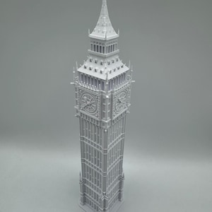 May include: A light grey, three-dimensional model of the Elizabeth Tower, commonly known as Big Ben. The structure features a tall, rectangular clock tower with intricate architectural details, including four clock faces and a pointed spire.
