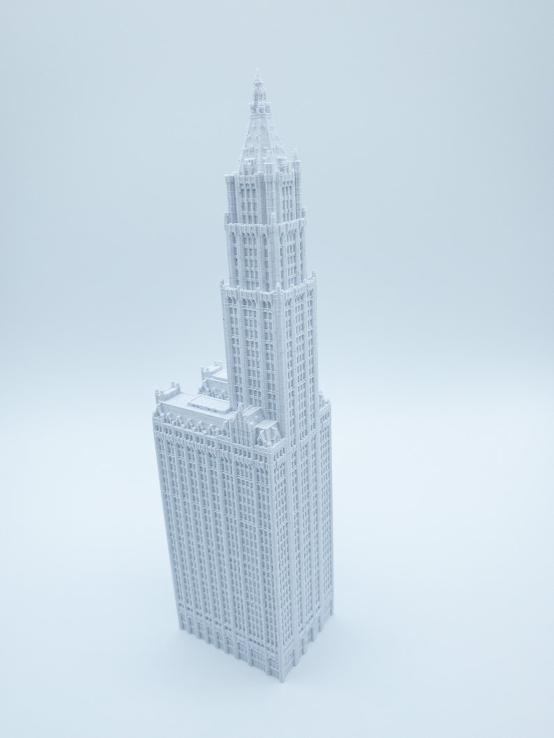K&ouml;nnte beinhalten: Ein wei&szlig;es 3D-gedrucktes Modell eines hohen Wolkenkratzers mit einem spitzen Dach und vielen Fenstern.