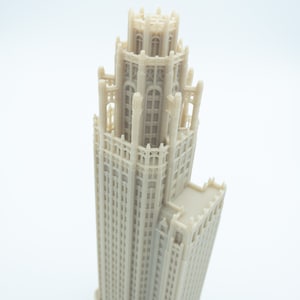 May include: A detailed 3D printed model of a tall, beige building with a decorative top and many windows.