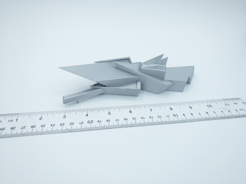 May include: A 3D printed model of a modern building with a geometric design. The model is made of a light gray plastic and is about 7 inches long.