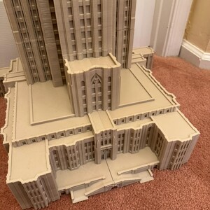 Puede incluir: Un modelo detallado de un edificio alto con un techo plano y una gran entrada. El edificio est&aacute; hecho de un material marr&oacute;n claro y tiene muchas ventanas. El modelo est&aacute; sentado sobre una alfombra marr&oacute;n.