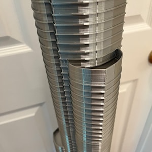 May include: A detailed model of a skyscraper, made from grey plastic, with a textured surface. The model is made up of many stacked layers, creating a realistic representation of a tall building.