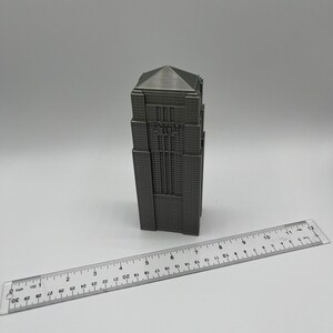 Peut inclure: Mod&egrave;le imprim&eacute; en 3D d'un gratte-ciel avec une finition grise. Le b&acirc;timent a un toit plat et une forme rectangulaire. Le mod&egrave;le mesure environ 15 cm de haut.