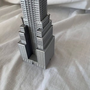 Puede incluir: Un modelo gris de un rascacielos con muchas ventanas y detalles. El modelo est&aacute; hecho de pl&aacute;stico y mide aproximadamente 25 cm de alto.
