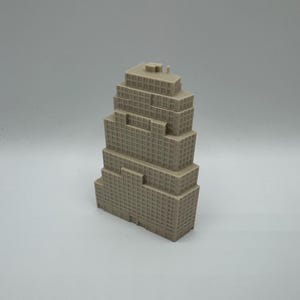 May include: A light grey, three-dimensional model of a stepped skyscraper building. The structure features a tiered, blocky design with numerous small, recessed square windows arranged in a grid pattern across all visible exterior facades.