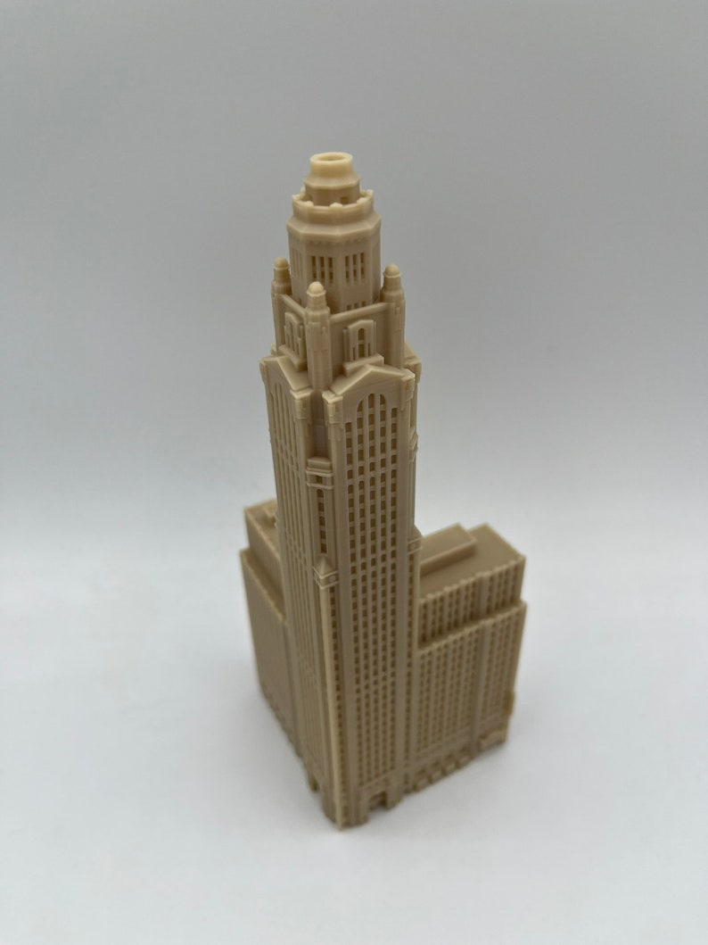 May include: A beige 3D printed model of a tall building with a decorative top and many windows.