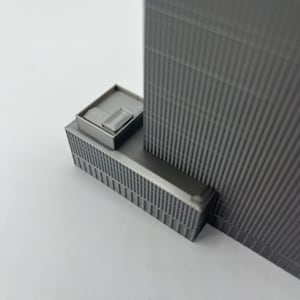 May include: A gray 3D printed model of a skyscraper with a small rooftop addition.