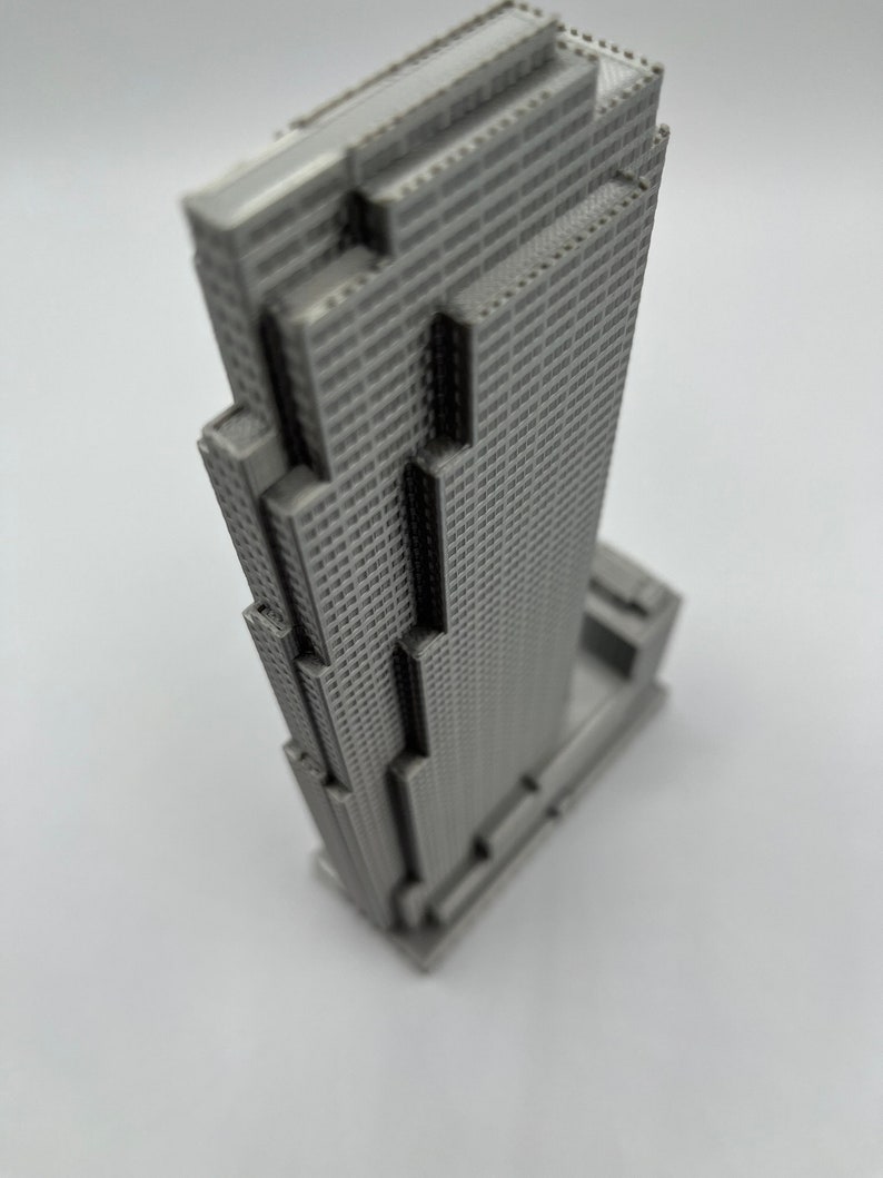 May include: A gray 3D printed model of a skyscraper building.