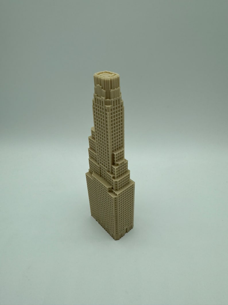 May include: A beige miniature model of a tall skyscraper with a flat roof and many windows.