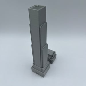 May include: A gray 3D printed model of a skyscraper with a rectangular base and a flat roof.