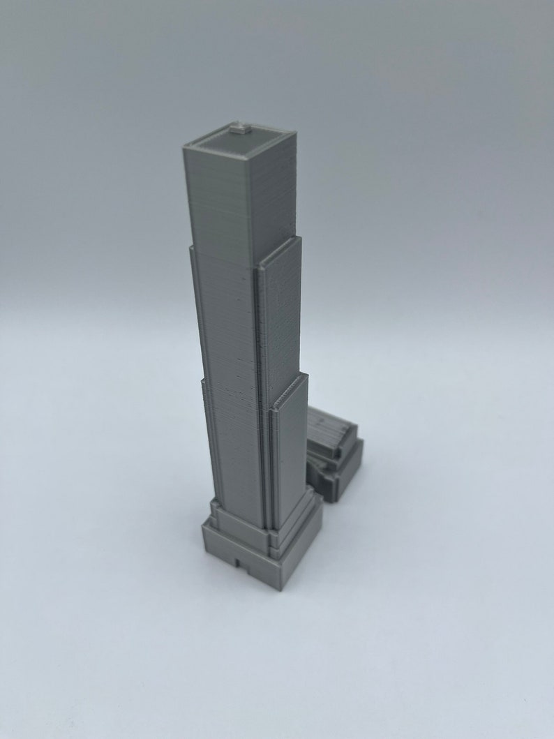 May include: A gray 3D printed model of a skyscraper with a rectangular base and a flat roof.