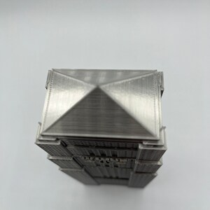 Peut inclure: Mod&egrave;le 3D imprim&eacute; en argent d'un gratte-ciel avec un toit en forme de pyramide.