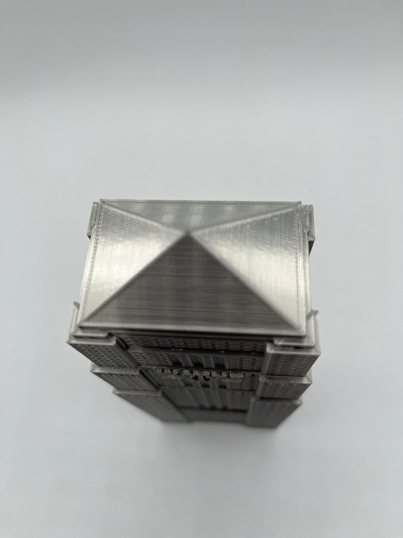 Peut inclure: Mod&egrave;le 3D imprim&eacute; en argent d'un gratte-ciel avec un toit en forme de pyramide.