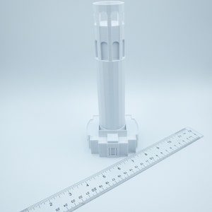 Może przedstawiać: Biały model 3D wydrukowany w 3D ikonicznego zabytku San Francisco, wieży Coit. Model ma około 15 cm wysokości i jest pokazany obok linijki w celu skalowania.