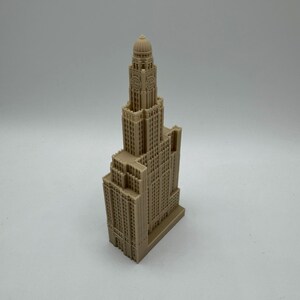 May include: A detailed miniature model of a tall, beige building with a domed roof and a clock face. The model is made of plastic and has a realistic design.